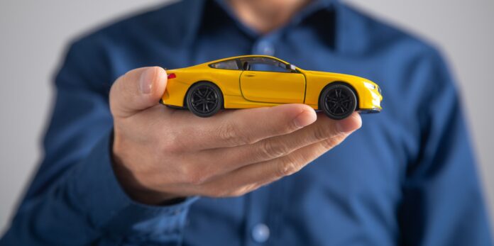 Sobiva liikluskindlustuse valimine - mees hoiab kollast mudelautot hellalt käes