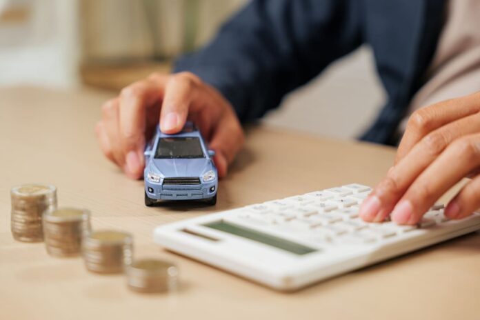 Liikluskindlustuse kalkulaator-valge kalkulaator, helesinine mudelauto ja mündivirnad reas