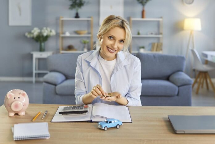 Liikluskindlustuse pakkumised - naeratav naine taskukalkulaatori, sinise mudelauto ja roosa hoiupõrsaga