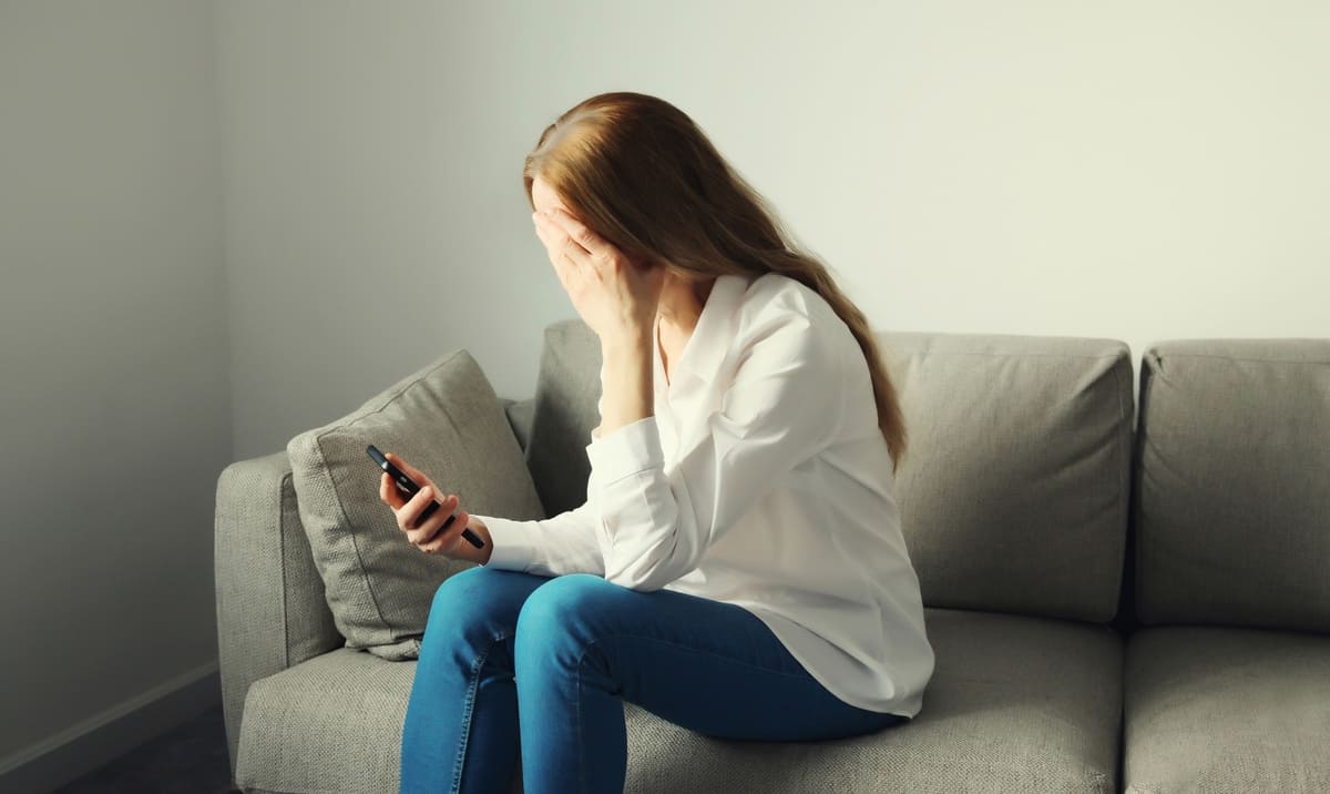 Automaatne liikluskindlustus -kurb naine telefoniga diivanil