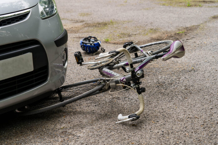 Auto kokkupõrge jalgratturiga ja liikluskindlustus - jalgratas on poolenisti auto all, kõrval kiiver